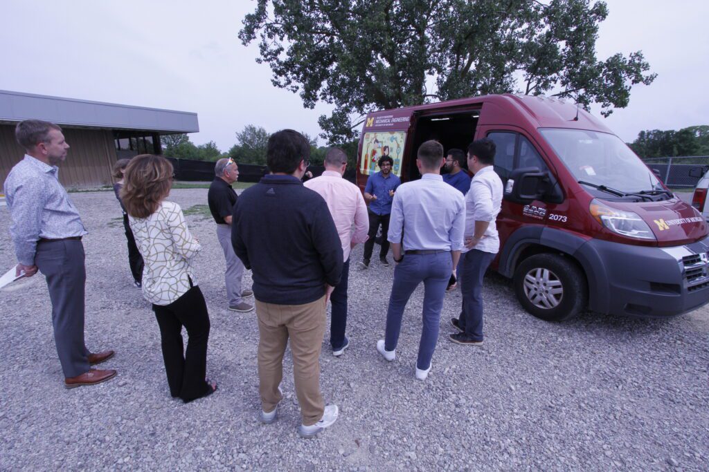 Nishant Jalgaonkar and Daniel Schulman present to Congressional Staffers in front of a red van.