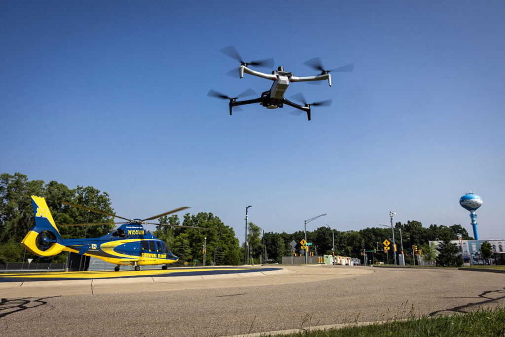 A drone flies in front of a U-M Survival Flight helicopter that landed at the the Mcity Test Facility on the University of Michigan’s North Campus.